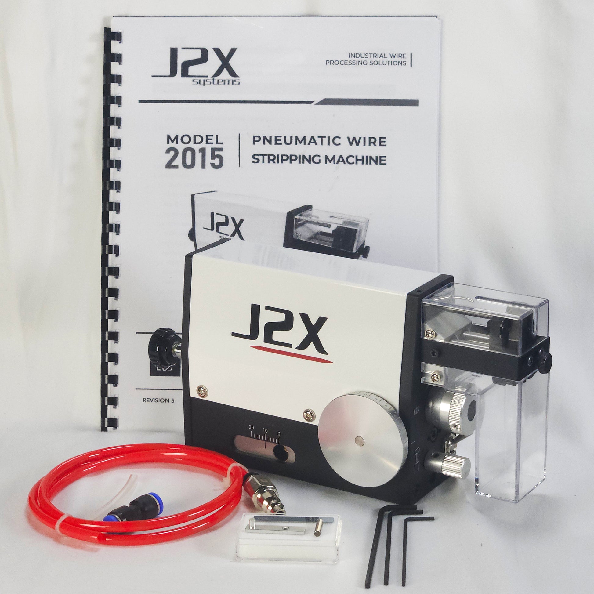 J2X Pneumatic Wire Stripping Machine Model 2015 kit, featuring the white and black pneumatic machine with a clear plastic safety shield and scrap container, a red pneumatic tube, accessories, and the original instruction manual.